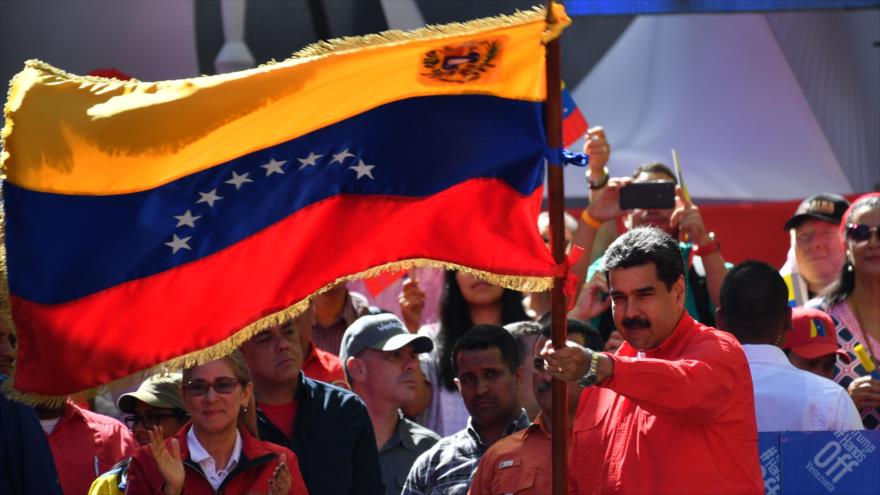 El presidente de Venezuela, Nicolás Maduro, enarbola la bandera nacional en un acto multitudinario en Caracas (capital), 23 de febrero de 2019. (Foto: AFP)