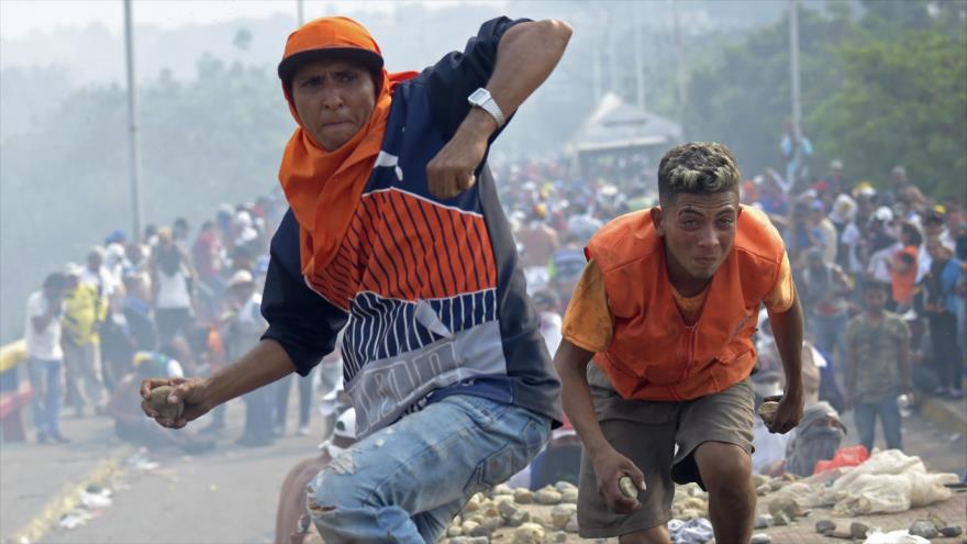 Dos manifestantes opositores lanzan piedras a los efectivos de la guardia fronteriza venezolana en la frontera con Colombia, 23 de febrero de 2019. (Foto: AFP)