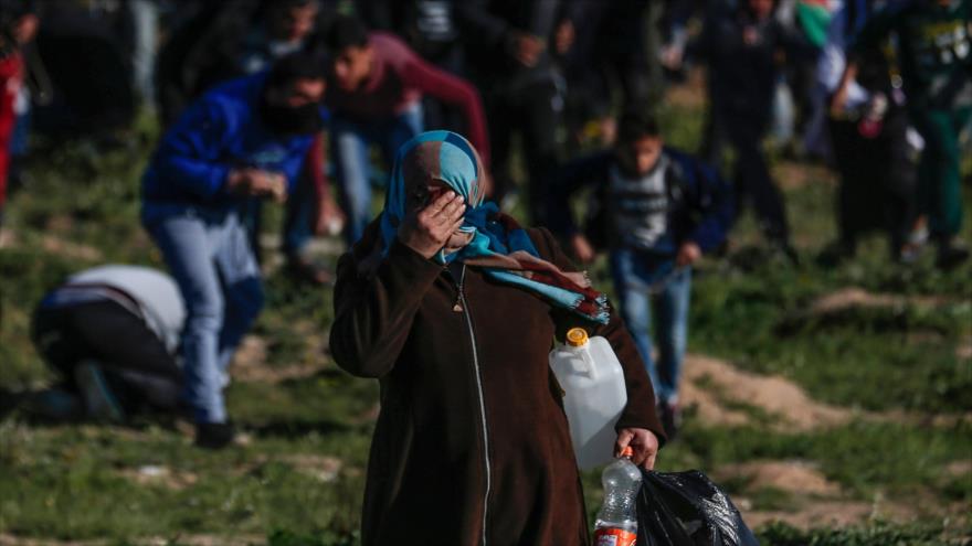 Mujer palestina se cubre la cara del humo de gas lacrimógeno lanzado por las fuerzas israelíes, este de la ciudad de Gaza, 8 de marzo de 2019. (Foto: AFP)