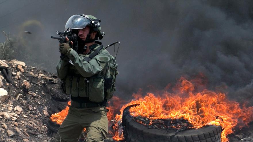 Un soldado israelí dispara contra manifestantes palestinos durante una protesta en Nablus, en la ocupada Cisjordania, 14 de julio de 2018. (Foto: AFP)