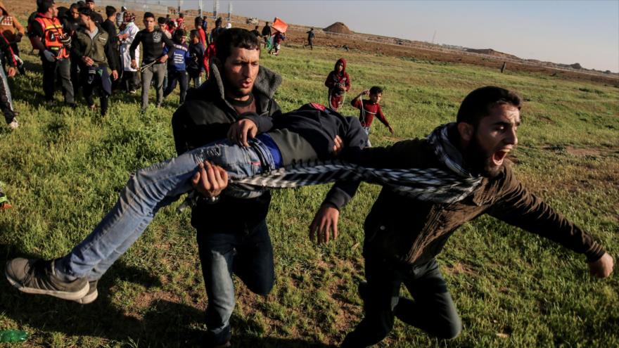Palestinos cargan a un manifestante herido en la frontera entre la Franja de Gaza y los territorios ocupados de Palestina, el 22 de marzo de 2019. (Foto: AFP)
