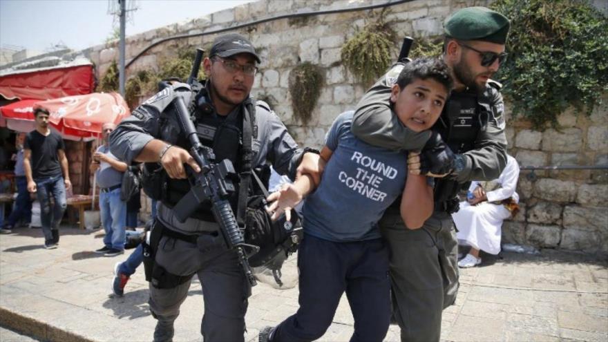 Fuerzas israelíes detienen a un menor palestino en una entrada principal al complejo de la mezquita de Al-Aqsa en la Ciudad Vieja de Al-Quds.