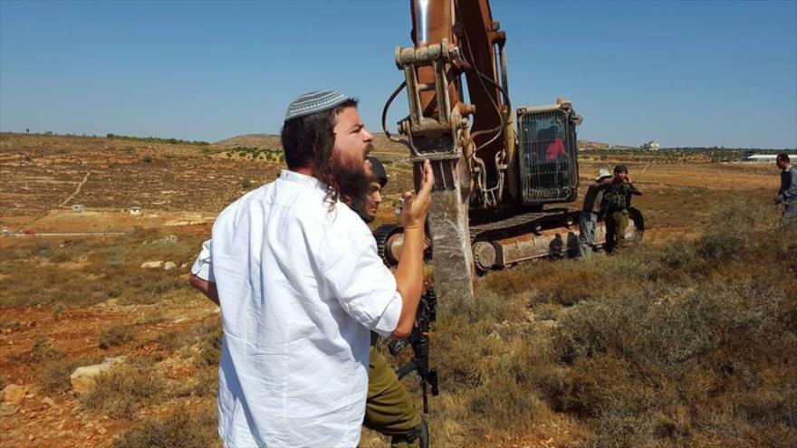 Un colono judío y un grupo de soldados israelíes, se encuentran en terrenos de los palestinos en la ocupada Cisjordania.