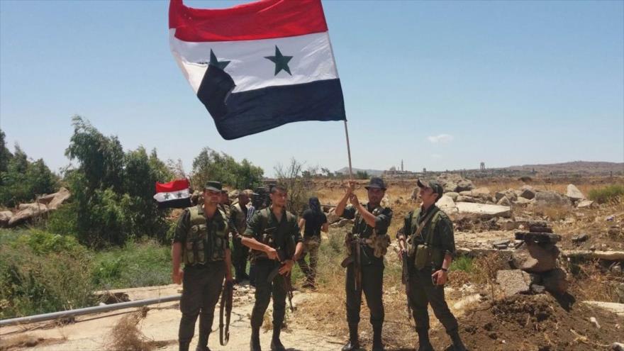 Soldados del Ejército sirio portan la bandera nacional en el pueblo de Al-Hamidiya, en la provincia suroccidental de Al-Quneitra, 26 de julio de 2018.