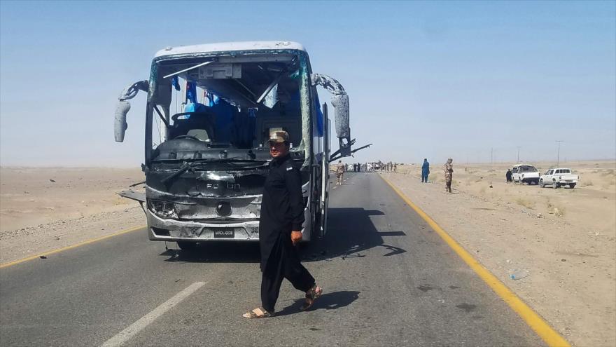 Un agente de seguridad paquistaní pasa delante de un autobús atacado por terroristas en Baluchistán (suroeste), 11 de agosto de 2018. (Foto: AFP)