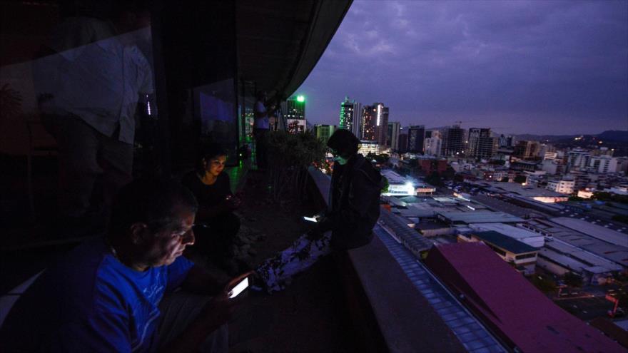 Algunos trabajadores observan sus móviles en las recientes cortes de energía eléctrica en Venezuela.