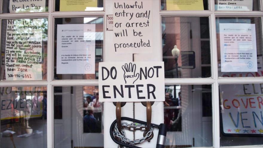 Activistas cubren edificio de embajada venezolana en EE.UU. con pancartas que dicen “Las manos fuera de Venezuela”, 25 de abril de 2019. (Foto: AFP)