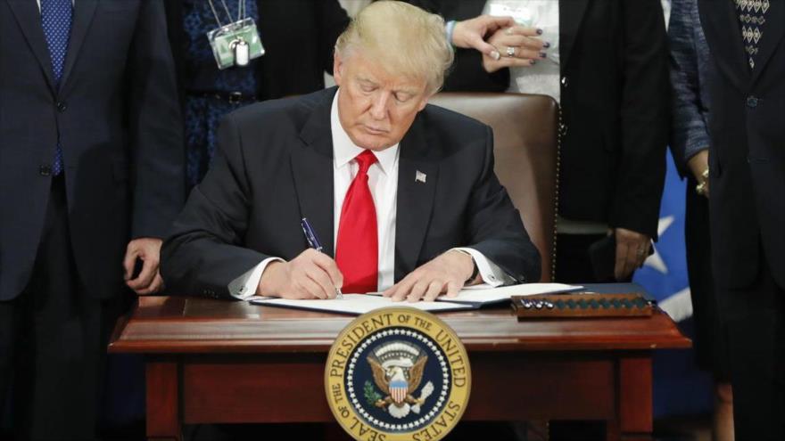 El presidente estadounidense, Donald Trump, firmando un decreto presidencial en su oficina en la Casa Blanca, en Washington.