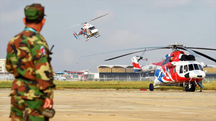 Un soldado camboyano observa un helicóptero ruso Kazan Ansat volar cerca de un Mil Mi-171ª2 en Nom Pen (capital), 20 de noviembre de 2018. (Foto: AFP)