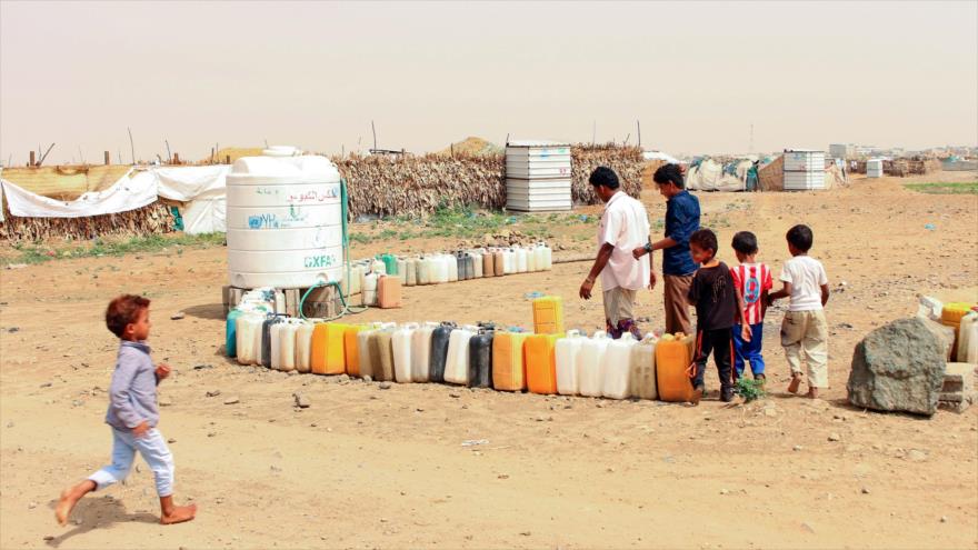 Yemeníes desplazados llenan recipientes de agua en un campamento improvisado en la provincia de Hajjah, 23 de junio de 2019. (Foto: AFP)
