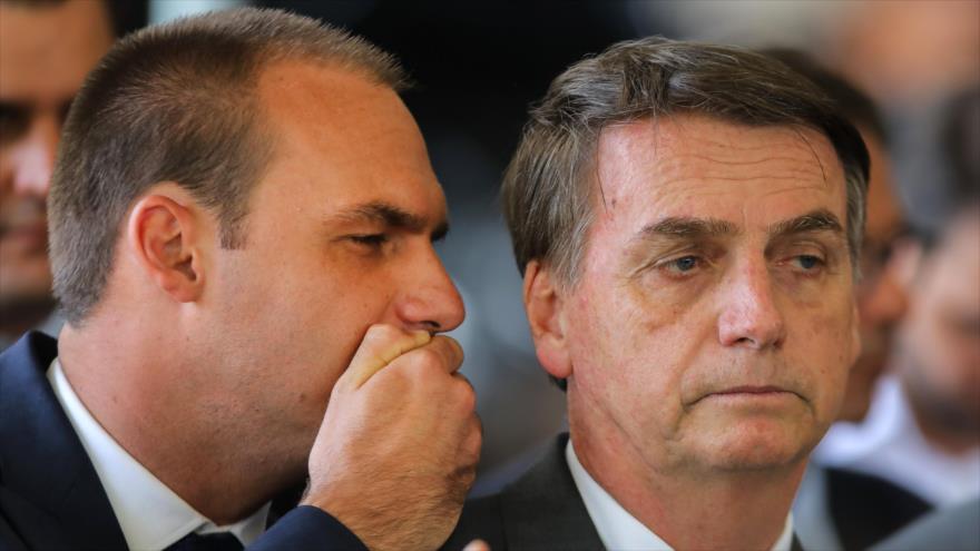 Jair Bolsonaro (dcha.), presidente de Brasil, escucha a su hijo Eduardo en un acto en la sede del Gobierno, 14 de noviembre de 2018. (Foto: AFP)