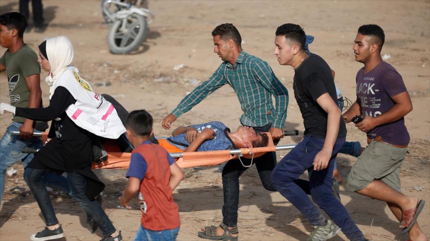 Paramédicos palestinos trasladan a un joven herido durante las protestas al este de Jan Yunis, en el sur de Gaza, 12 de julio de 2019. (Foto: AFP)