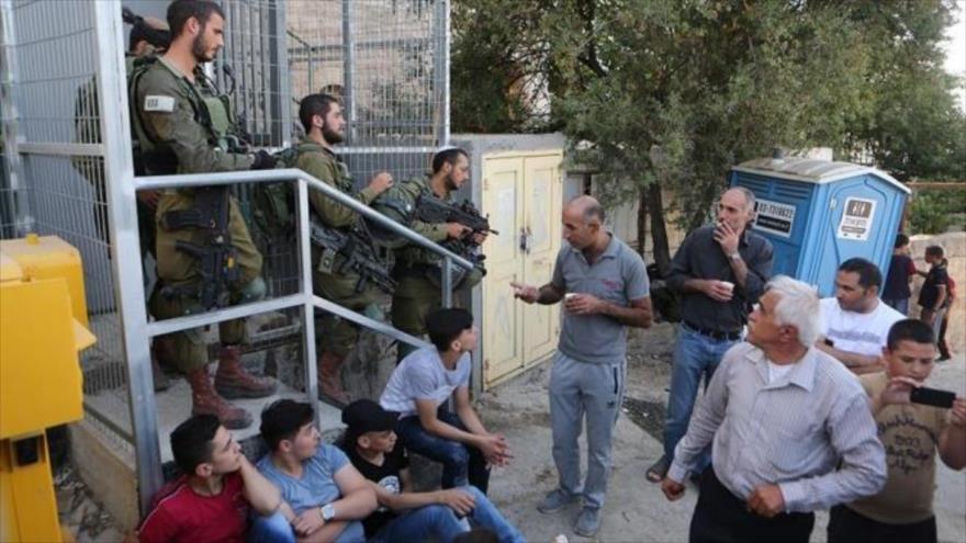 Civiles palestinos parados en un puesto militar israelí en la ocupada Cisjordania.