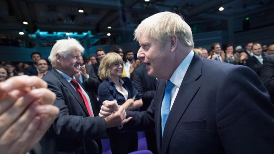 El nuevo premier británico, Boris Johnson (dcha.), saluda a su padre Stanley Johnson (izda.) en Londres, 23 de julio de 2019. (Foto: AFP)
