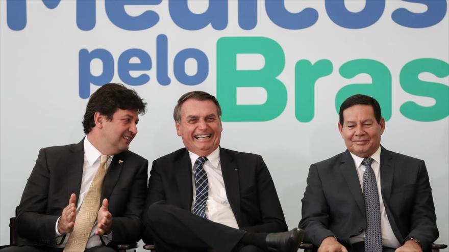 El presidente de Brasil, Jair Bolsonaro (centro), se ríe en un mitin sobre la denominada iniciativa de su Gobierno, “Médicos por Brasil”, 1 de agosto de 2019.