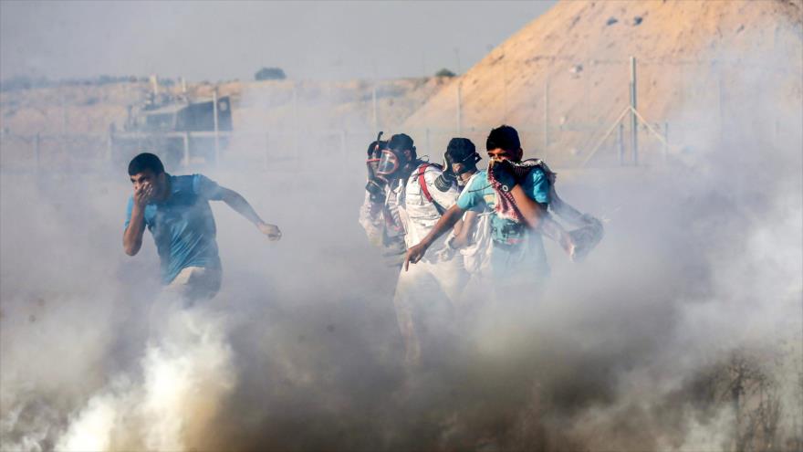 Palestinos huyen del gas lacrimógeno lanzado por las fuerzas israelíes durante las protestas en la Franja de Gaza, 5 de julio de 2019. (Foto: AFP)