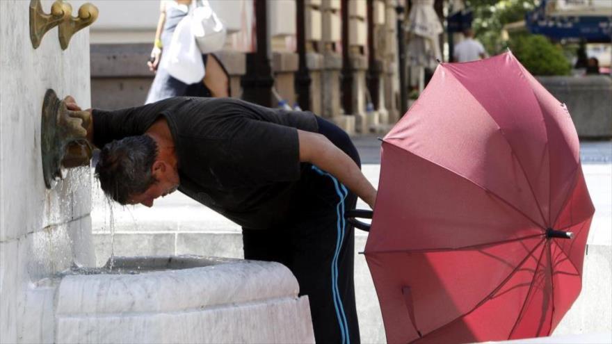 Un hombre se refresca en una fuente en Belgrado a causa del calor que se registra en la zona.