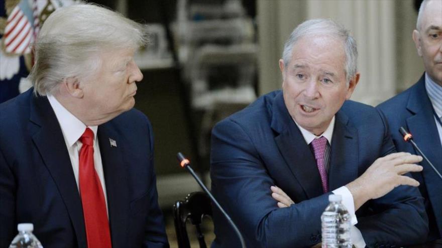El presidente de EE.UU., Donald Trump, escucha atentamente a su benefactor donante, el multimillonario Stephen Schwarzman, en un acto.
