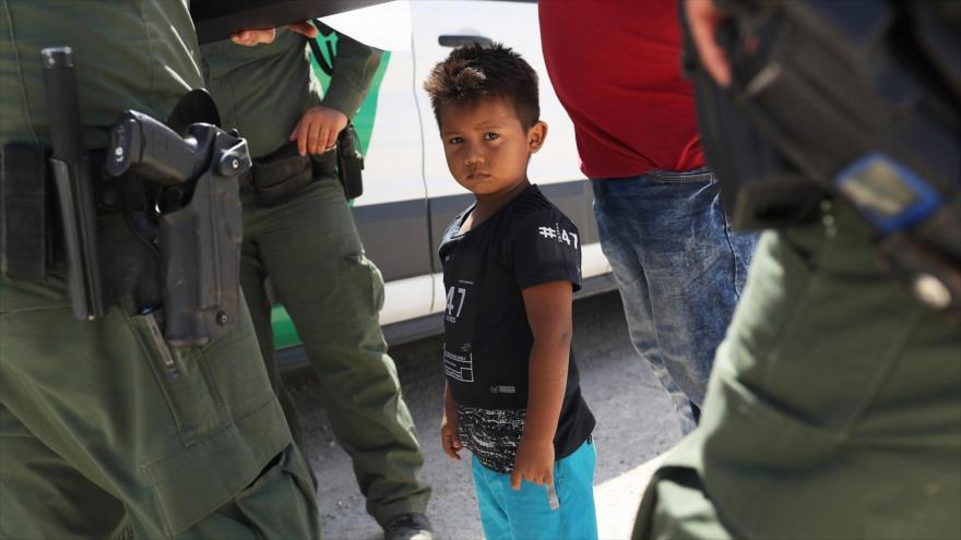 Un niño acompañado por su padre, retenido en la frontera sureña de EE.UU. con México. 