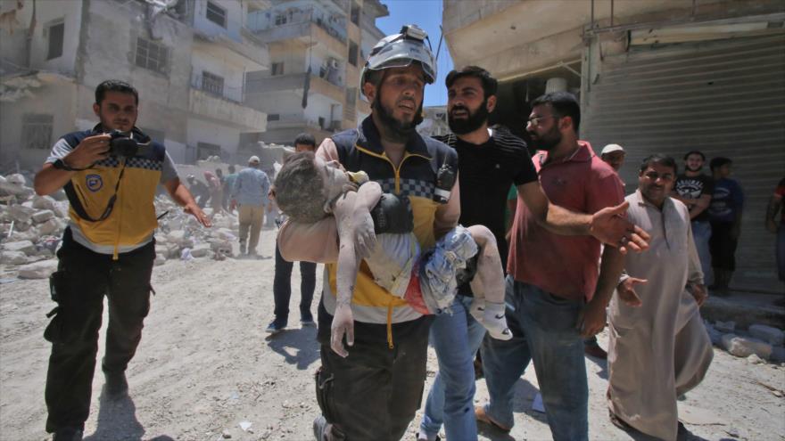 Un miembro de los llamados cascos blancos fotografiado con un niño muerto en sus brazos en una localidad en Idlib, Siria, 27 de julio de 2019. (Foto: AFP)