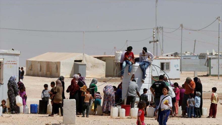 Refugiados sirios hacen cola para obtener agua en el campo de Zaatari cerca de Jordania.