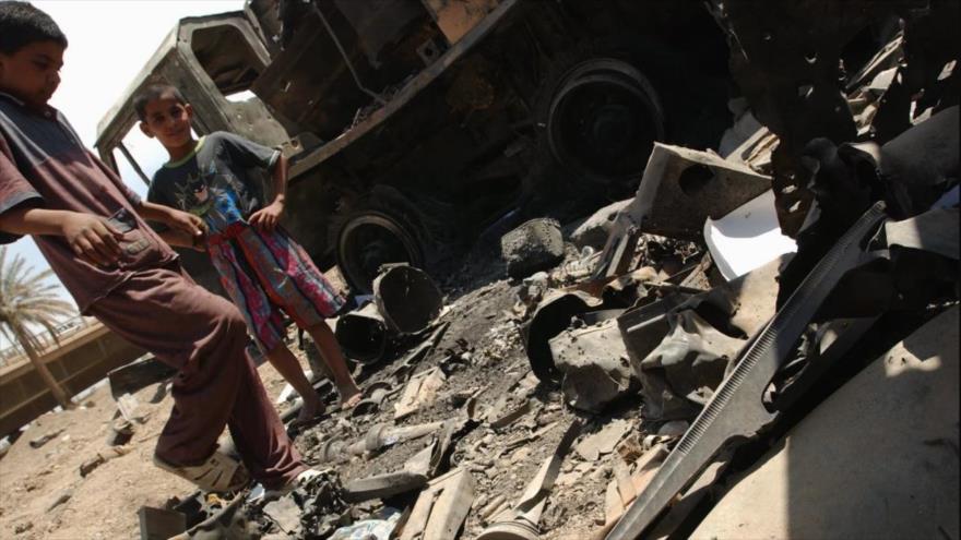 Dos niños iraquíes juegan entre vehículos incendiados por ataques de EE.UU. en Bagdad, la capital iraquí, 3 de mayo de 2003.