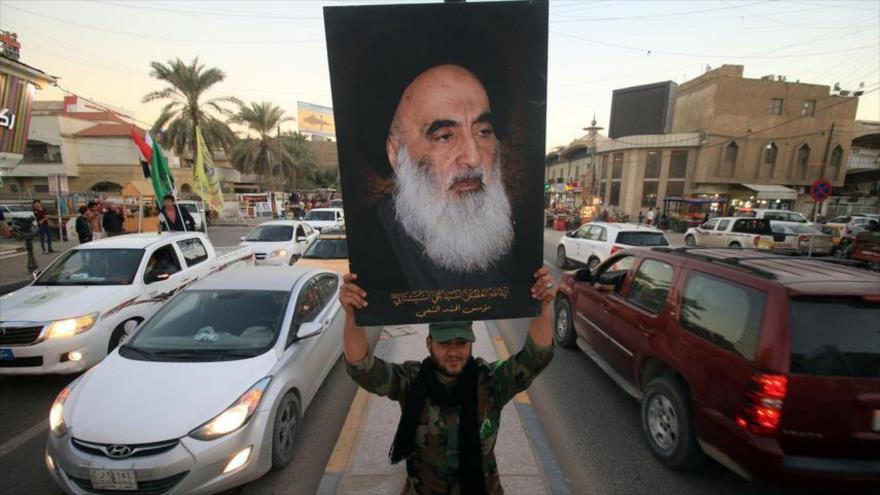 Un iraquí sujeta un retrato del clérigo chií Ali Sistani en la ciudad de Basora, sur de Irak.