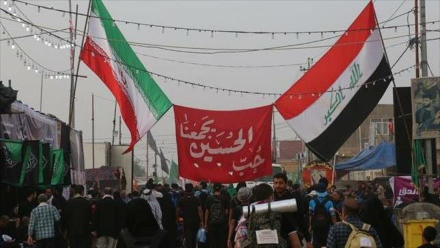 Los peregrinos de Arbain sostienen banderas de Irak e Irán mientras caminan entre las ciudades santas iraquíes de Nayaf y Karbala, octubre de 2018.