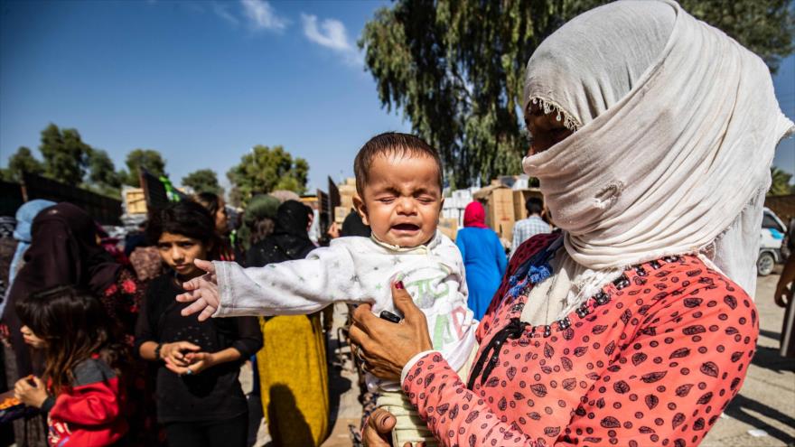 Sirios desplazados que huyeron de sus hogares en la ciudad de Ras al-Ain reciben ayuda humanitaria en Tal Tamr, 12 de octubre de 2019. (Foto: AFP)