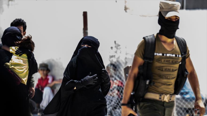 Las fuerzas kurdas escoltan a dos esposas de combatientes de EIIL en el campamento de Al-Hol, en el norte de Siria, 23 de julio de 2019.