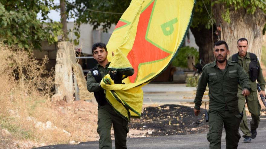 Fuerzas kurdas portan una bandera en la ciudad de Kobani, norte de Siria, 18 de octubre de 2019. (Foto: AFP)