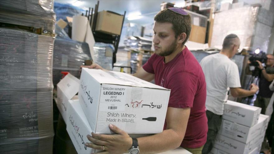 Un trabajador israelí sostiene cajas de productos fabricados en los territorios ocupados palestinos.
