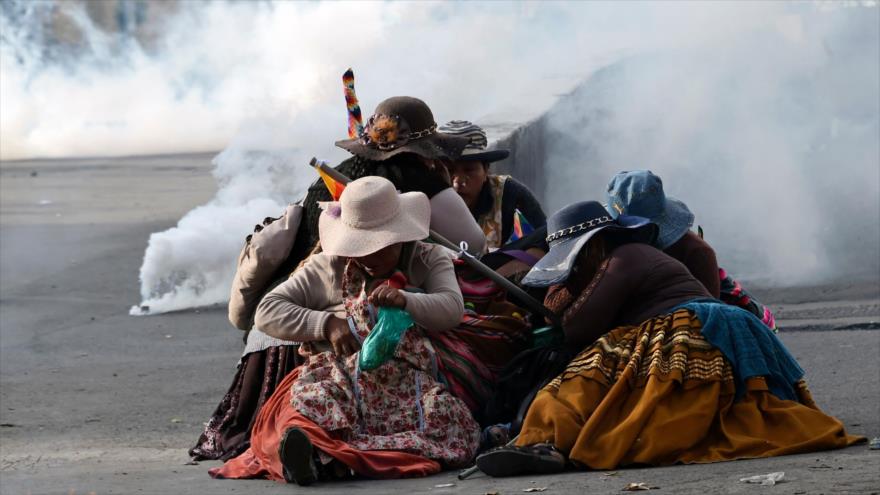 Mujeres indígenas bolivianas se protegen de los gases lacrimógenos durante una protesta contra el gobierno de facto, en La Paz, 15 de noviembre de 2019. (Foto: AFP)