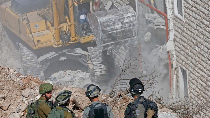 Las fuerzas israelíes vigilan mientras una excavadora demuele una casa palestina en la ocupada Cisjordania, 25 de septiembre de 2019. (Foto: AFP)