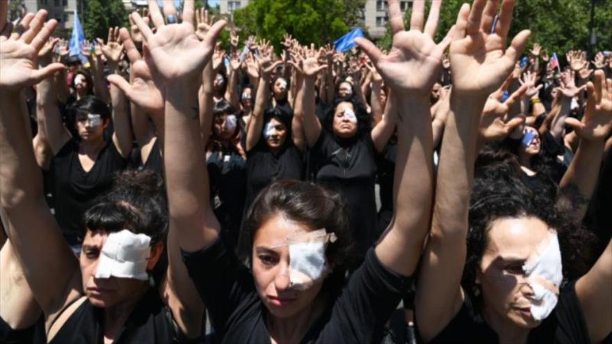 Chilenos, con un ojo tapado, levantan la mano en protesta por la violencia policial, después de que algunos manifestantes resultaran heridos en los ojos con perdigones.