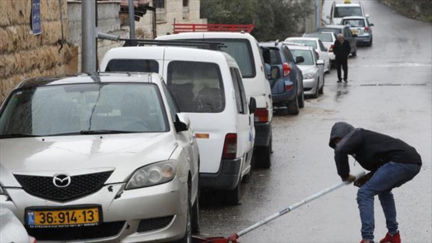 Un palestino repara una rueda pinchada de su coche en el barrio Shuaffat, Al-Quds, 9 de diciembre de 2019.