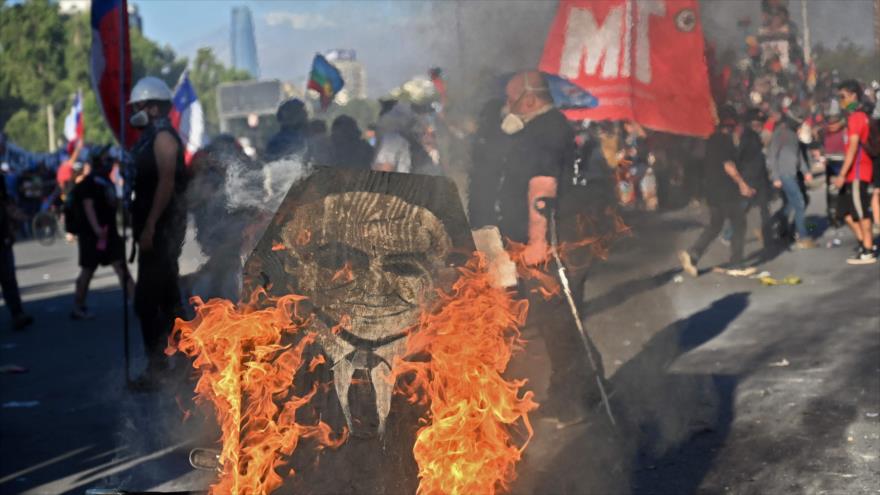 Un ataúd con la imagen del presidente chileno, Sebastián Piñera, arde en llamas durante una protesta en Santiago, 29 de noviembre de 2019. (Foto: AFP)