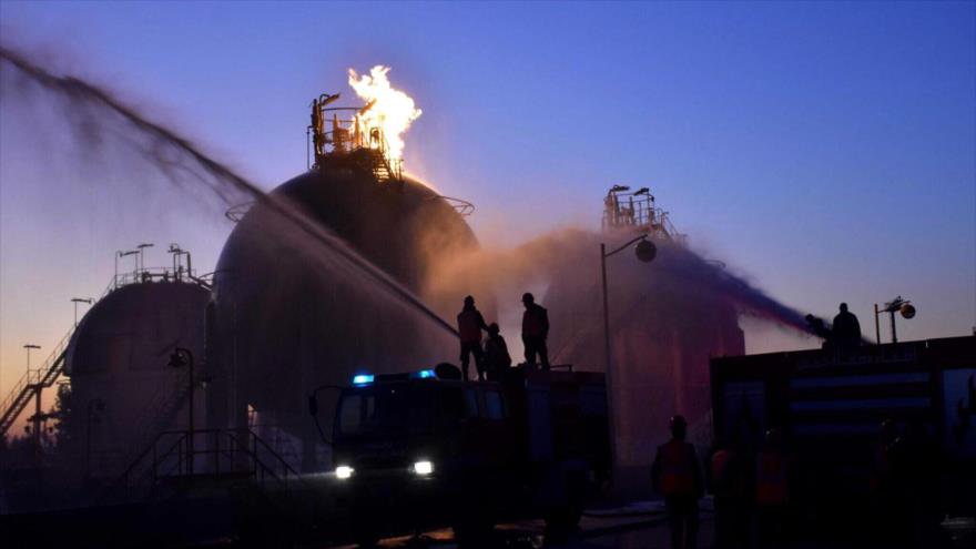 Bomberos tratan de extinguir el incendio provocado por un ataque a una instalación petrolera en Homs, centro de Siria, 21 de diciembre de 2019. (Foto: SANA)