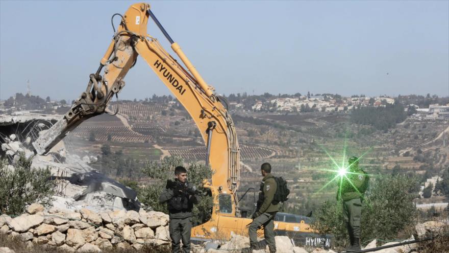 Fuerzas israelíes tratan de mantener alejados a palestinos, cuya vivienda está siendo demolida, Cisjordania, 19 de noviembre de 2019. (Foto: AFP)