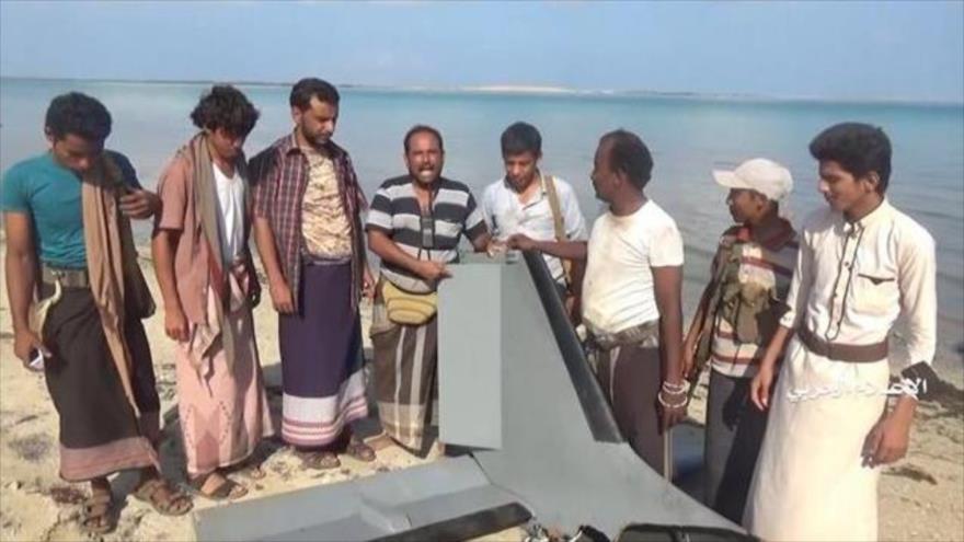 Varios yemeníes en pie junto a los restos del dron espía de Arabia Saudí derribado en la región fronteriza de Jizan.