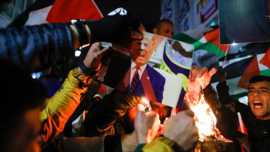 Palestinos prenden fuego fotografías del presidente de EE.UU., Donald Trump, y del premier israelí, Benjamín Netanyahu, en Ramalá, 28 de enero de 2020.