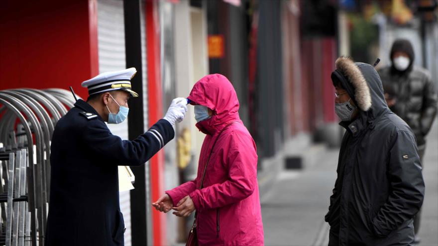 Un agente de seguridad chequea la temperatura de las personas que ingresan a Yu Park en Shanghái, este de China, 6 de febrero de 2020. (Foto: AFP)