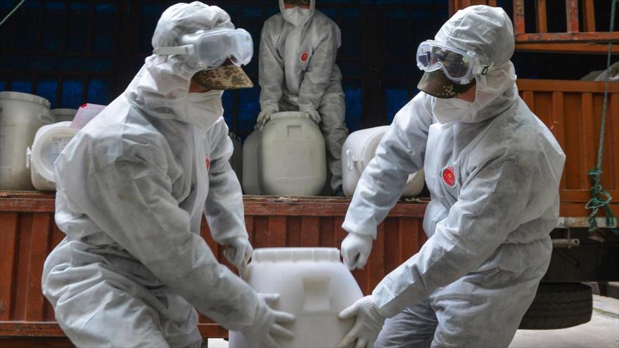 Policía china con vestimentas protectoras transfirieron baldes de desinfectante en condado de Yunmeng, en las afueras de ciudad de Xiaogan. (Foto: AFP)