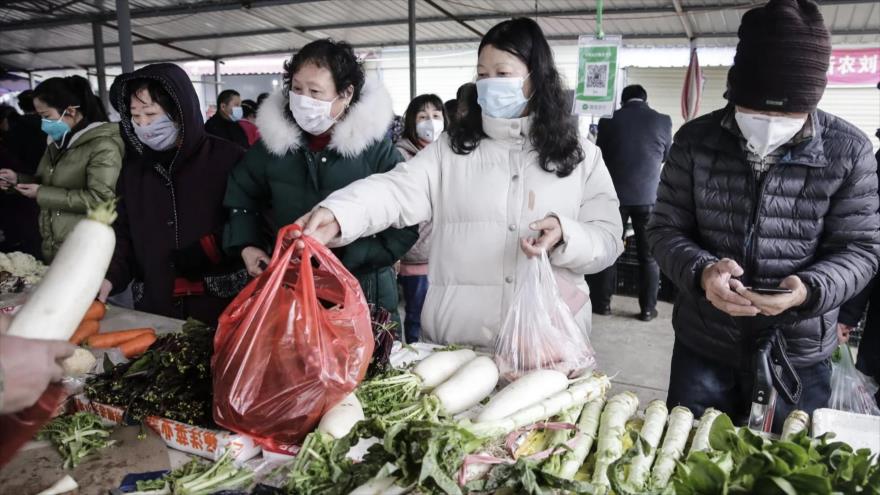 Chinos hacen sus compras protegidos con mascarillas ante el temor de contagio del coronavirus.