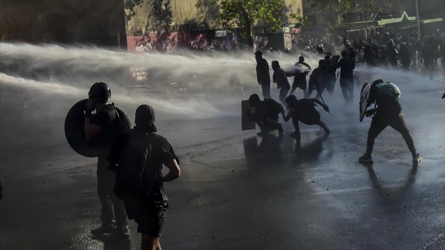 Cañones de agua rocían a manifestantes durante protesta contra el presidente chileno Sebastián Piñera, Santiago, 21 de febrero de 2020. (Foto: AFP)