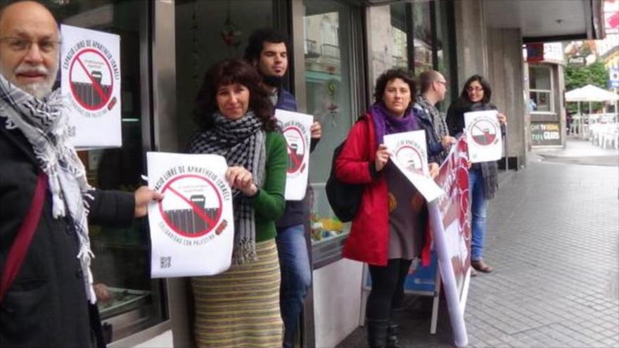 Españoles portan carteles con el sello de Espacios Libre de Apartheid Israelí.