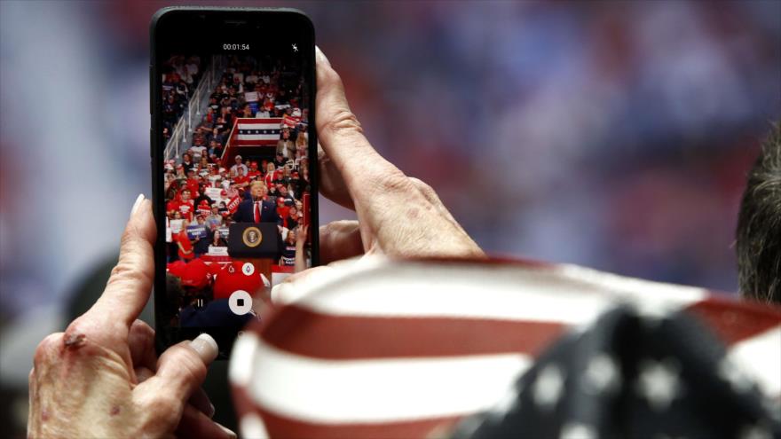 Un partidario filma al presidente de EE.UU., Donald Trump, mientras habla durante un mitin electoral en Charlotte, 2 de marzo de 2020. (Foto: AFP)