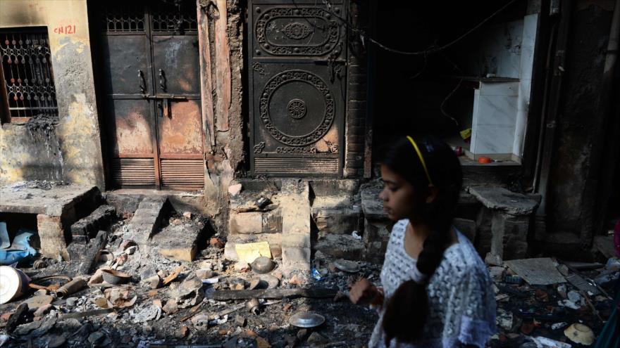 Un residente pasa junto a un edificio quemado en una zona residencial en Nueva Delhi, La India, 1 de marzo de 2020. (Foto: AFP)