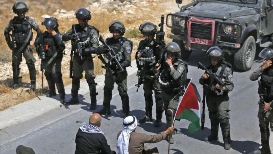Palestinos se sientan ante tropas israelíes en una protesta contra la expropiación de sus tierras por parte de Israel en Kafr Malik en la Cisjordania ocupada.