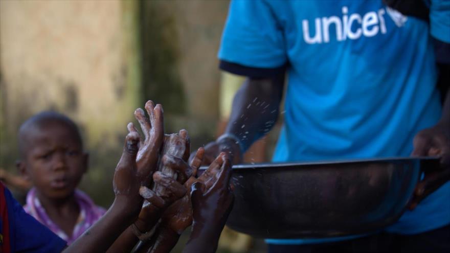 Un miembro de Unicef muestra a los niños cómo lavarse las manos para evitar el contagio.